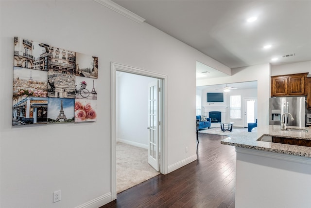 kitchen featuring sink, ceiling fan, dark hardwood / wood-style floors, stainless steel refrigerator with ice dispenser, and light stone counters