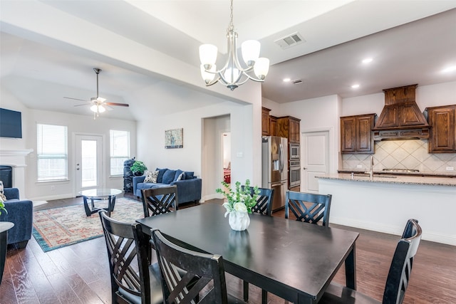 dining area featuring lofted ceiling, dark hardwood / wood-style flooring, and ceiling fan with notable chandelier