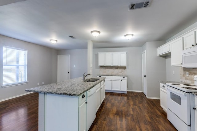 kitchen with sink, decorative backsplash, light stone counters, a center island with sink, and white appliances