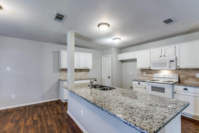 kitchen featuring white cabinetry, sink, a kitchen island with sink, light stone countertops, and white appliances