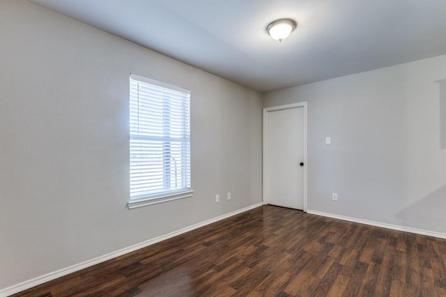 spare room featuring dark wood-type flooring and plenty of natural light