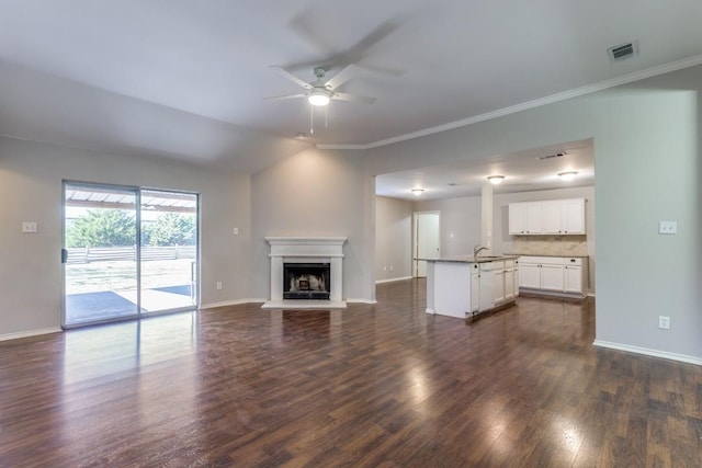 unfurnished living room featuring ceiling fan, ornamental molding, dark hardwood / wood-style floors, and sink