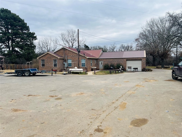 view of front of house featuring metal roof, brick siding, an attached garage, and aphalt driveway