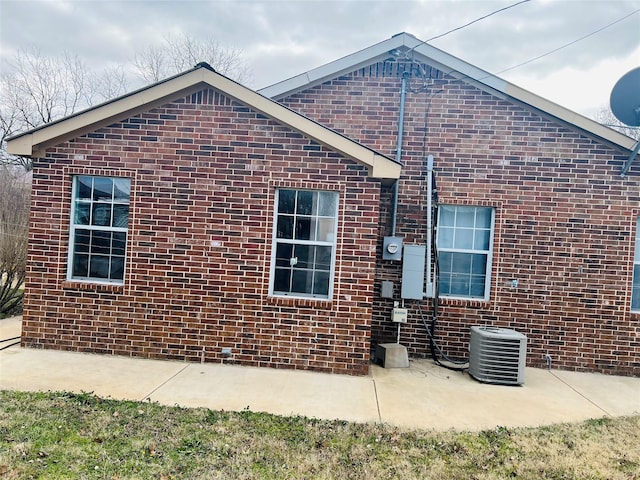 view of front of property with a patio area, brick siding, and central air condition unit