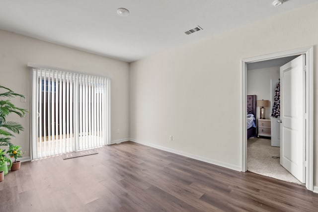 spare room featuring baseboards, visible vents, and wood finished floors