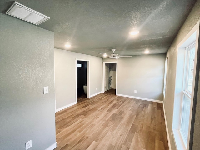 unfurnished room featuring ceiling fan, light hardwood / wood-style flooring, and a textured ceiling