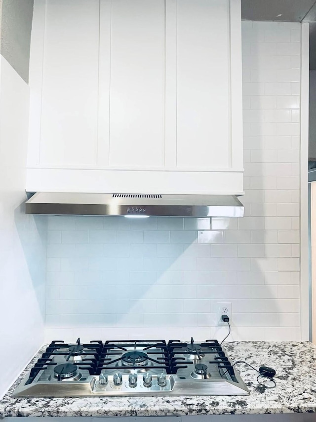 details with white cabinetry, tasteful backsplash, light stone countertops, and stainless steel gas cooktop