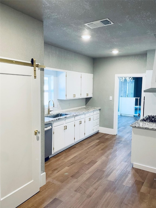 kitchen with appliances with stainless steel finishes, a barn door, light hardwood / wood-style flooring, and white cabinets