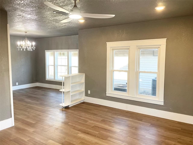 spare room featuring ceiling fan with notable chandelier, hardwood / wood-style floors, and a textured ceiling