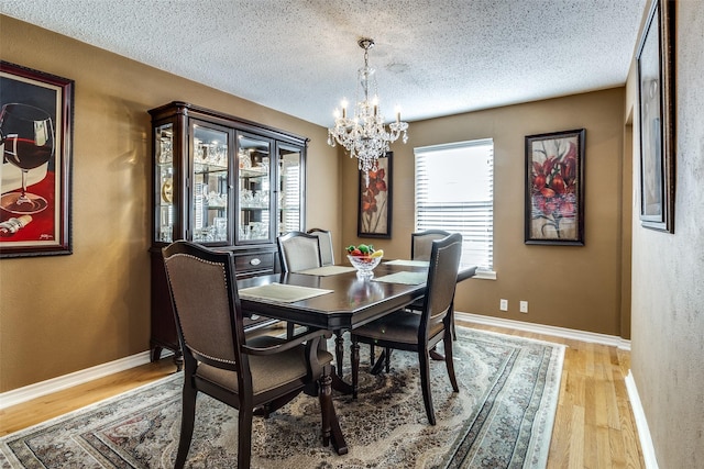 dining space featuring light hardwood / wood-style floors, a chandelier, and a textured ceiling