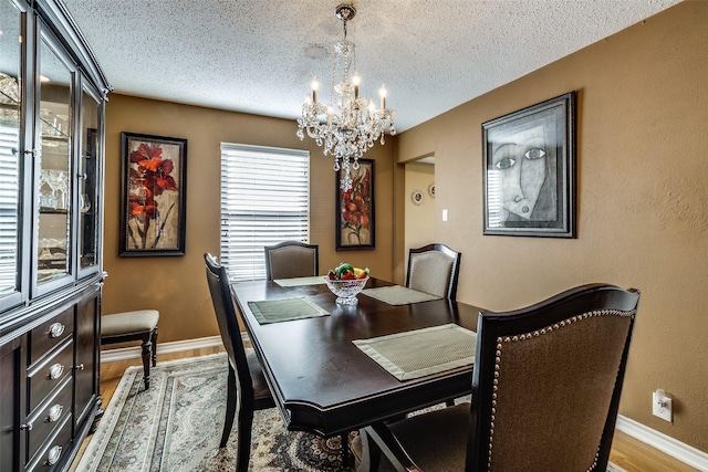 dining space featuring an inviting chandelier, light hardwood / wood-style floors, and a textured ceiling