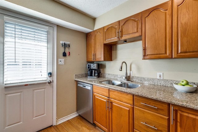 kitchen featuring dishwasher, sink, light stone countertops, a textured ceiling, and light hardwood / wood-style flooring