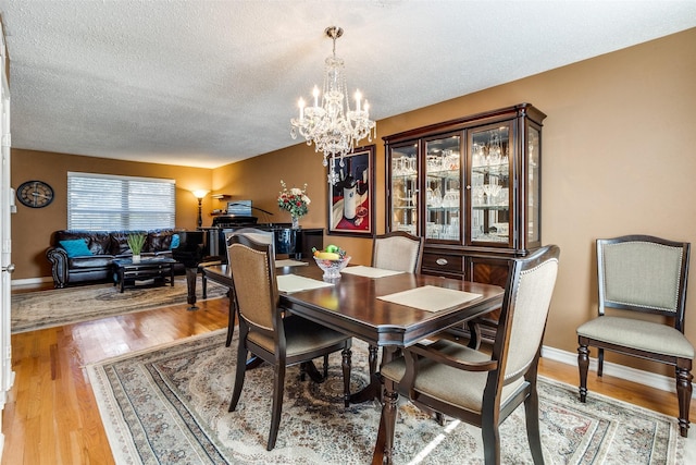 dining area featuring hardwood / wood-style floors, a textured ceiling, and a chandelier