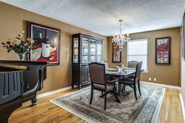 dining area with hardwood / wood-style flooring, a chandelier, and a textured ceiling