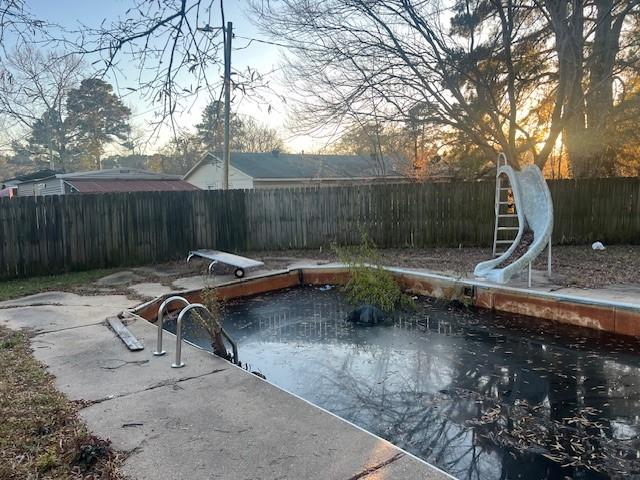 view of pool with a diving board and a water slide