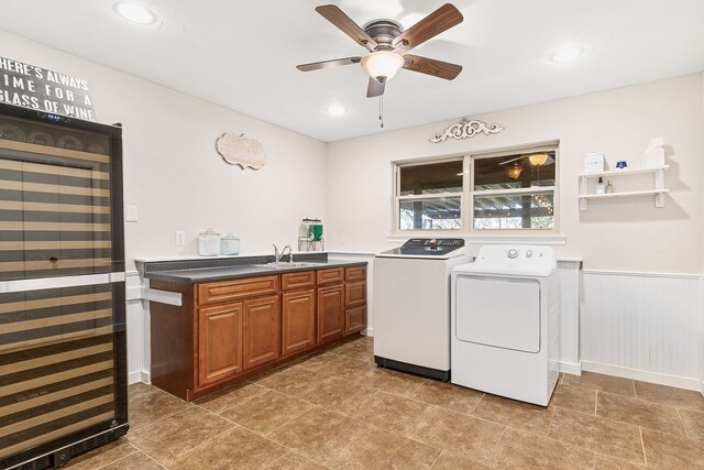 laundry area with washing machine and clothes dryer, sink, cabinets, ceiling fan, and beverage cooler