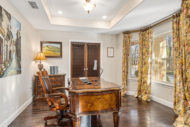 home office with dark hardwood / wood-style floors and a raised ceiling