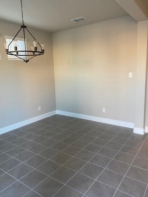 unfurnished dining area with a chandelier and dark tile patterned floors