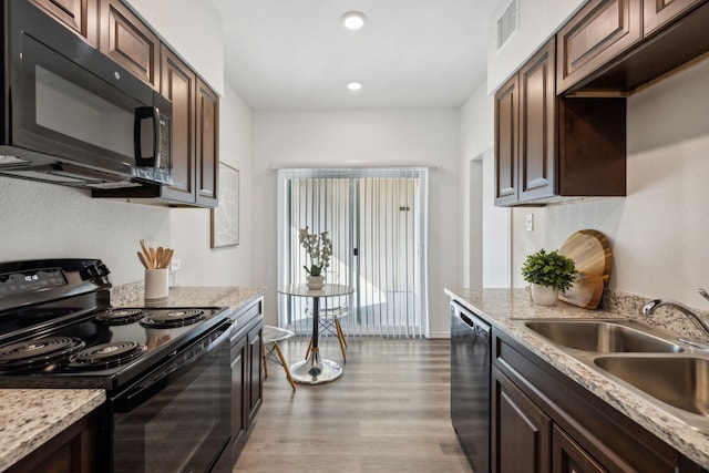 kitchen with sink, light stone counters, dark brown cabinetry, and black appliances