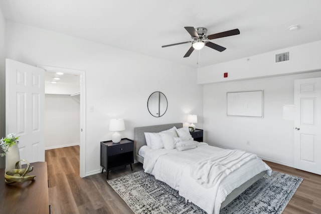 bedroom featuring a spacious closet, dark hardwood / wood-style floors, a closet, and ceiling fan