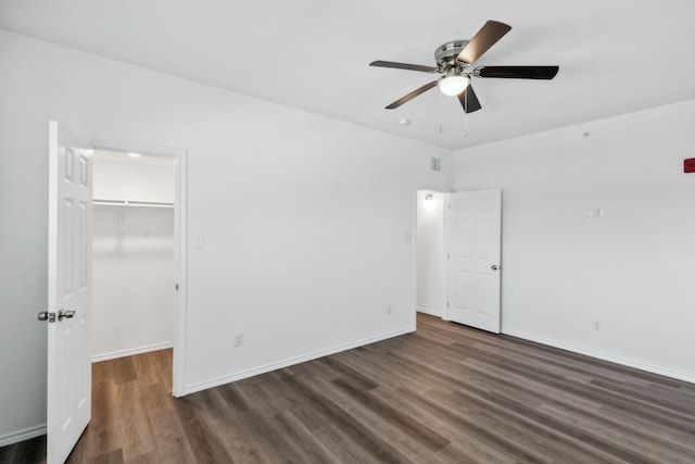 unfurnished bedroom featuring dark hardwood / wood-style floors, ceiling fan, a spacious closet, and a closet