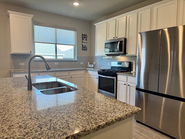 kitchen with white cabinetry, sink, stainless steel appliances, and light stone countertops