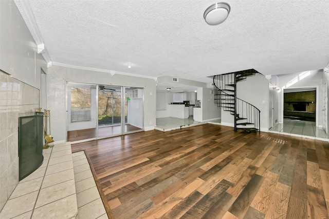 unfurnished living room with ornamental molding, a tile fireplace, and a textured ceiling