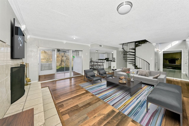 living room featuring crown molding, a tiled fireplace, and a textured ceiling