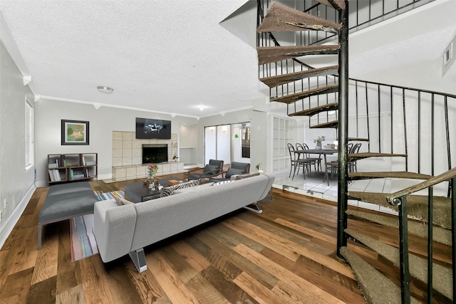 living room featuring ornamental molding, a fireplace, hardwood / wood-style floors, and a textured ceiling