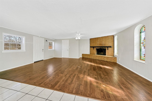 unfurnished living room with a fireplace, a textured ceiling, light hardwood / wood-style flooring, and a wealth of natural light