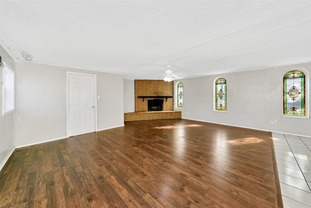 unfurnished living room with dark hardwood / wood-style flooring, a brick fireplace, a textured ceiling, and ceiling fan