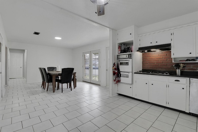 321 Bowles Ct, Kennedale, TX 76060 - kitchen featuring white cabinets, under cabinet range hood, dark countertops, white appliances, and decorative backsplash