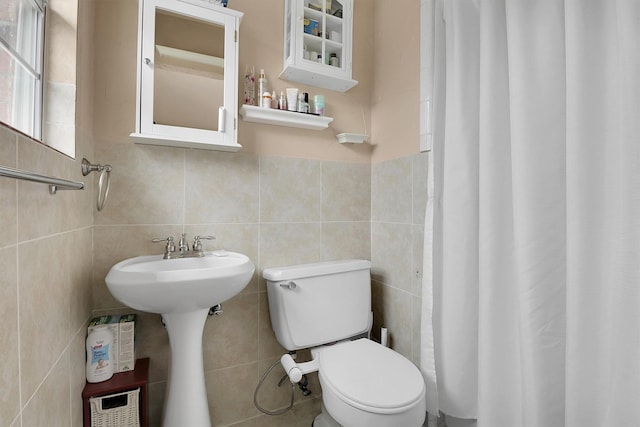 bathroom featuring toilet, sink, and tile walls