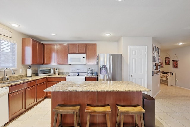 kitchen featuring white appliances, light tile patterned flooring, a sink, and a kitchen breakfast bar