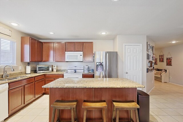 kitchen featuring sink, white appliances, light tile patterned floors, and a kitchen bar