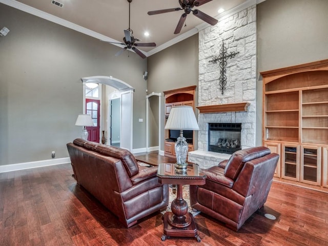 living room featuring a towering ceiling, ornamental molding, a fireplace, and dark hardwood / wood-style flooring