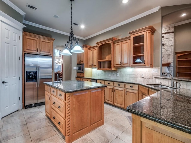 kitchen with a kitchen island, appliances with stainless steel finishes, pendant lighting, sink, and dark stone counters