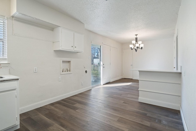 foyer with baseboards, a textured ceiling, a chandelier, and dark wood-style flooring