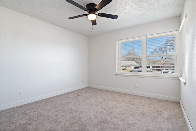 empty room with carpet floors, ceiling fan, a textured ceiling, and baseboards