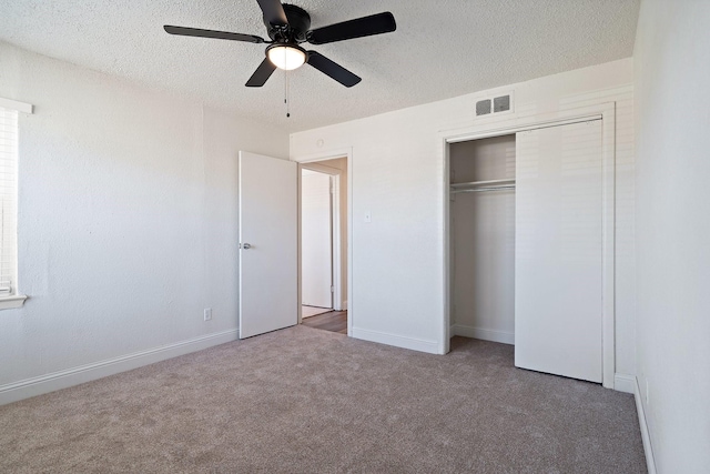 unfurnished bedroom featuring light carpet, a textured ceiling, ceiling fan, and a closet