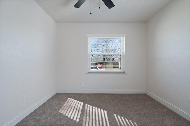 spare room featuring ceiling fan, dark carpet, and a textured ceiling