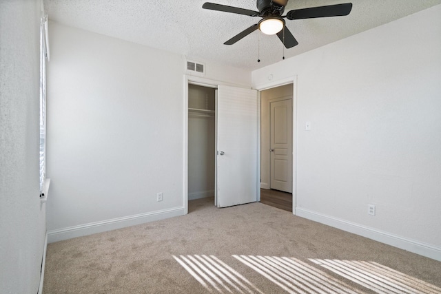 unfurnished bedroom featuring light colored carpet, a textured ceiling, ceiling fan, and a closet