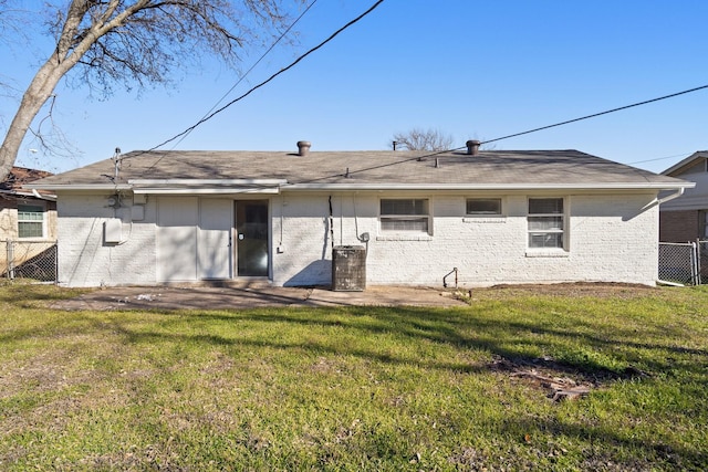 rear view of property with a yard, brick siding, and fence