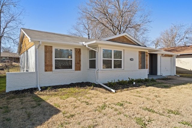 view of front of house with an attached garage, fence, a front lawn, and brick siding