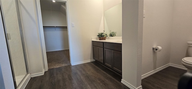 bathroom featuring vanity, hardwood / wood-style floors, a shower with shower door, and toilet