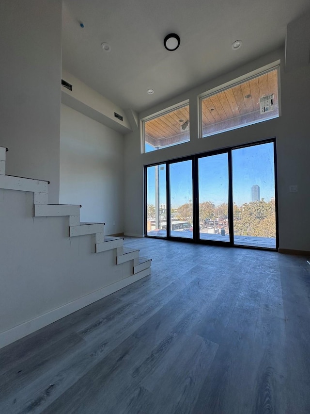 unfurnished living room with a towering ceiling and hardwood / wood-style floors