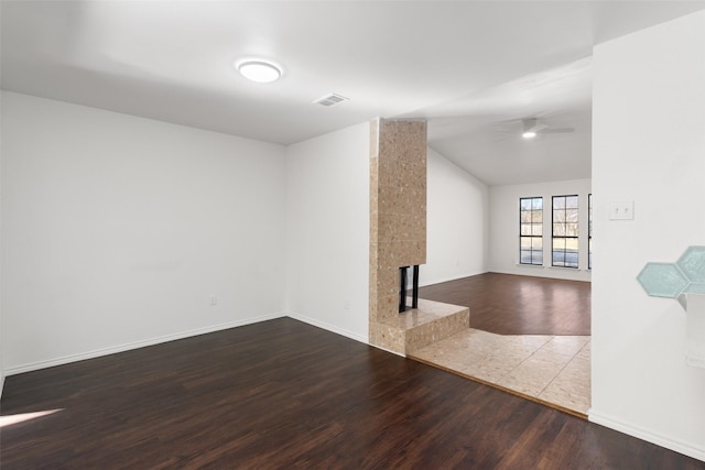 unfurnished living room featuring ceiling fan, a fireplace, wood-type flooring, and vaulted ceiling