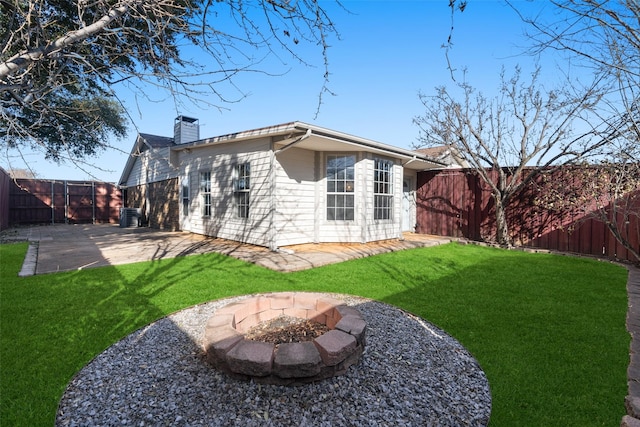 rear view of property with central AC, a yard, a patio area, and a fire pit