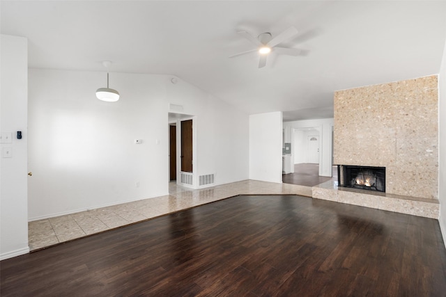 unfurnished living room with hardwood / wood-style flooring, a tile fireplace, vaulted ceiling, and ceiling fan