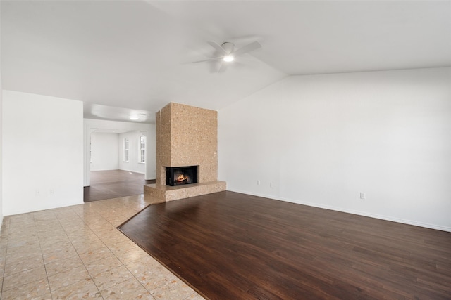 unfurnished living room featuring lofted ceiling, a fireplace, ceiling fan, and light tile patterned flooring